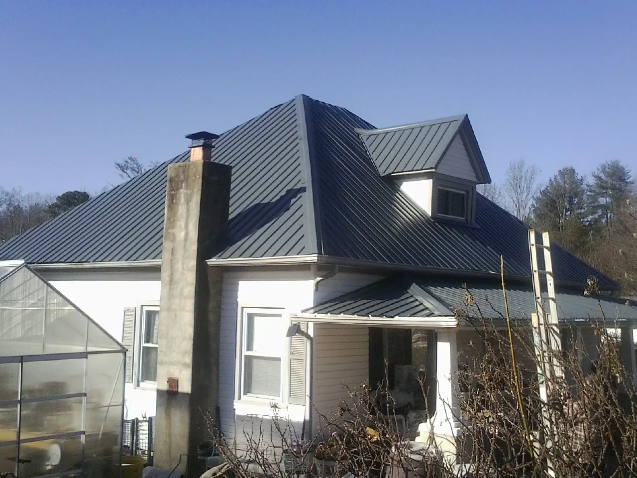 Dark blue standing seam metal roof on a white farmhouse with dormer — Slate & Tile Roof Repair by Roofing Brothers in Simla