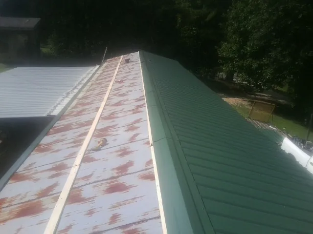 Old rusted panels beside newly installed green metal roofing — Wind Damage Roof Repair by Roofing Brothers in Simla