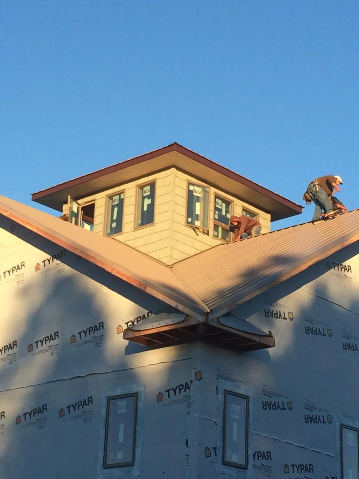 Roofers working around a rooftop cupola on a new metal roof at sunset — Roof Waterproofing in Simla by Roofing Brothers